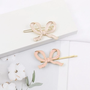 Lot de deux barrettes à cheveux nœud en émail rose sur un support blanc élégant