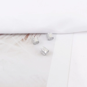 Primer plano de anillos plateados para trenzas con relieve de corona sobre plumas blancas