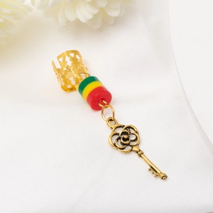 Gros plan d'un bijou de cheveux pour dreadlocks doré avec perles colorées et pendentif clé
