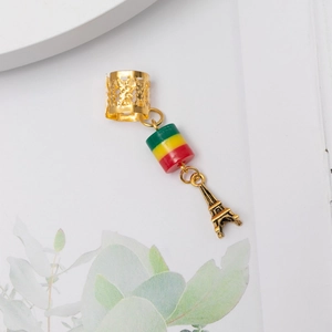 Détail de l'anneau à cheveux doré avec perle tricolore et pendentif tour Eiffel ciselé
