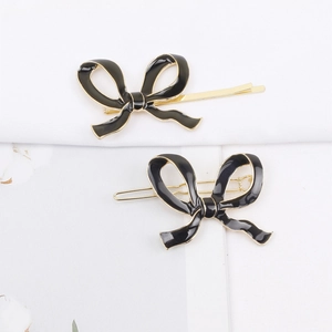 Détail macro des barrettes nœud en émail noir avec une finition dorée élégante