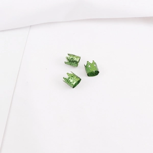 Detalle de tres cuentas de aluminio verde para rastas con forma de corona y diseño hueco