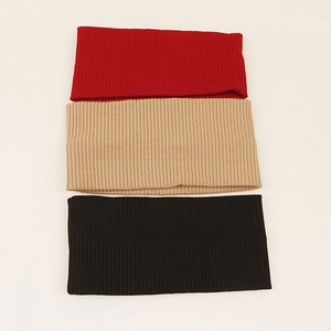 Detailed close-up of three knitted elastic headbands in red, khaki, and black colors