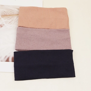 Detailed view of knitted ribbed headbands in orange, pink, and navy blue fabric textures