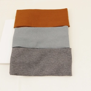 Detailed knit texture of three elastic yoga headbands in yellow, light gray, and dark gray