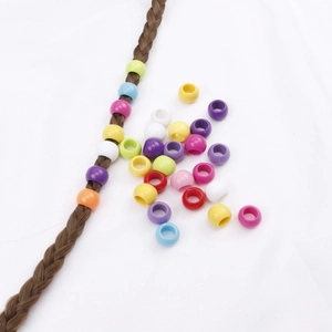 Colorful plastic barrel hair beads styled on brown braids and scattered on white fabric
