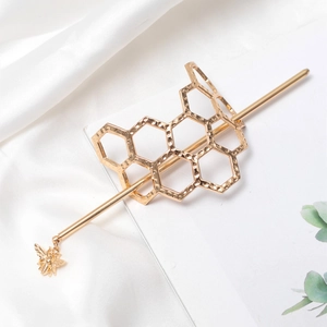 Golden honeycomb hair pin with a 3D bee pendant on elegant white silk background