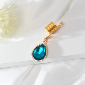Makro-Detail eines goldenen Spiral-Haarrings mit blauem Kristall-Tropfenanhänger