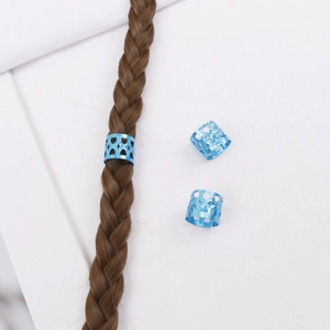 Détail d'une bague de tresse en aluminium bleu avec motif cœur sur des cheveux tressés