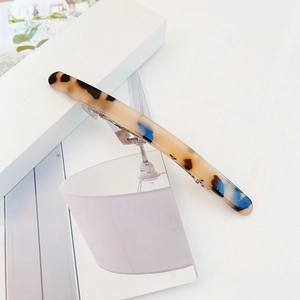 Macro detail of tortoiseshell acetate hair clip with premium blue and brown textures