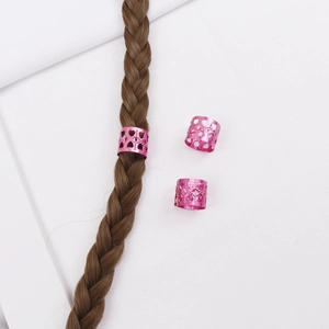 Détail des anneaux de cheveux en métal rose avec motifs de cœur évidés pour tresses