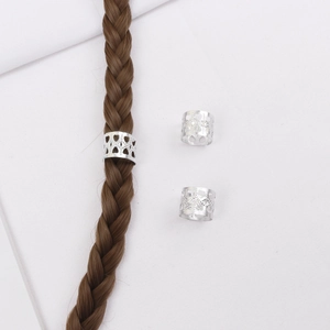 Détail de bagues à cheveux coeur argentées sur des décorations de tresses marron