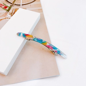 Detailed close-up of a marble-patterned acetate spring hair clip on a minimalist background