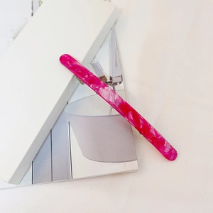 Detail of rose pink marble acetate hair clip on minimalist lifestyle magazine background