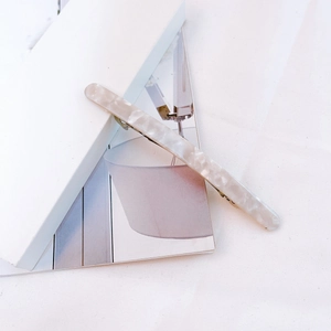 Detail of elegant cream marble acetate hair clip with gold metal spring mechanism