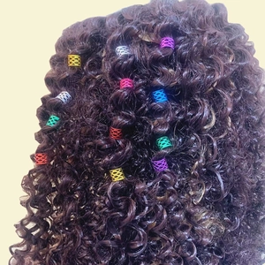 Detalle macro de anillos metálicos huecos de colores para trenzas y rastas decorativas