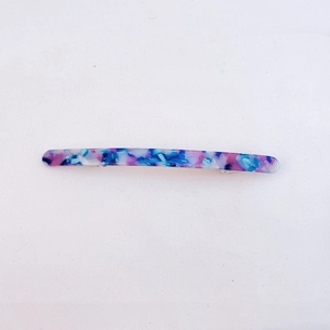 Macro detail of slim acetate hair clip with pink and blue marble pattern and metal spring