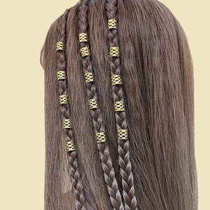 Detalle de puños de metal dorado hueco para trenzas y decoración de rastas sobre el cabello