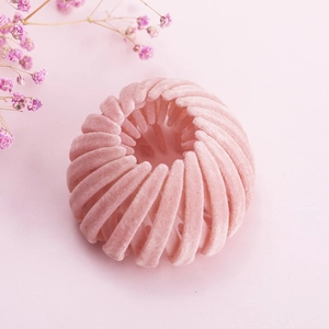 Vue macro d'une pince à cheveux rose poudré en velours avec un design extensible en nid d'oiseau