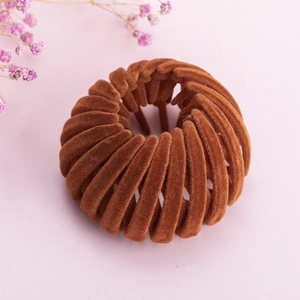 Pince à cheveux nid d'oiseau marron floqué pour chignon sur fond rose doux