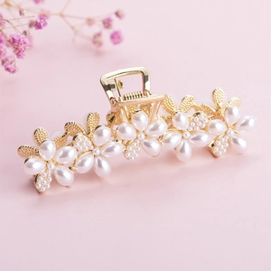 Elegant gold metal hair claw clip featuring pearl flower design on soft pink background