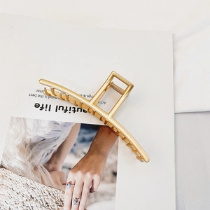 Elegant matte gold metal hair claw clip with geometric design on a white magazine