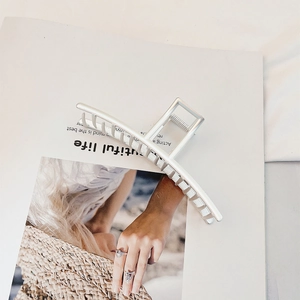 Minimalist matte silver metal shark hair claw clip displayed on an aesthetic magazine background