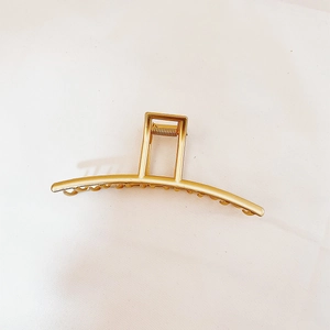 Macro view of matte gold metal hair claw clip with strong spring and grip teeth