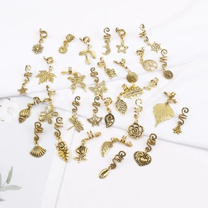 Flat lay of antique gold alloy dreadlock charms with various butterfly and leaf pendants