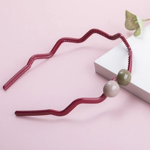 Deep red wavy headband with decorative gray and olive green beads on a pink background
