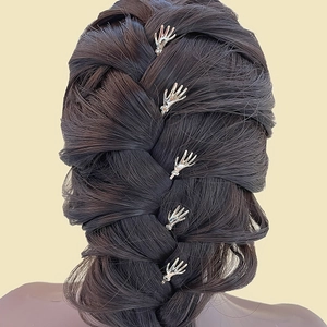 Five silver hand-shaped hair clips styled on a dark braided hairstyle against a beige background