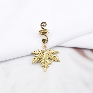 Close-up of golden maple leaf pendant with spiral ring for hip hop dreadlock styling