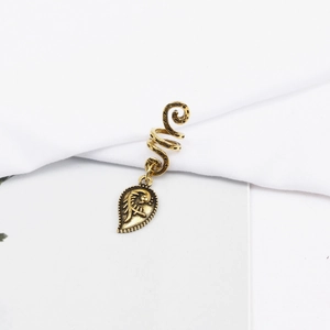 Macro shot of antique gold spiral dreadlock ring with detailed leaf-shaped ethnic pendant