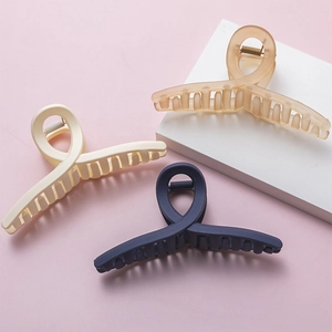 Large matte resin hair claws in cream, amber, and navy blue on geometric stands