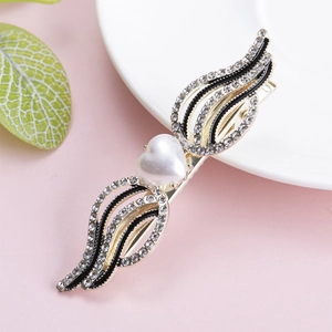 Close-up of golden wing hair clip with heart pearl and sparkling rhinestones