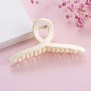 Close-up of a large cream-colored matte hair claw clip with minimalist cross design