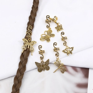 Close-up of golden alloy spiral hair rings with butterfly and dragonfly charms on braids