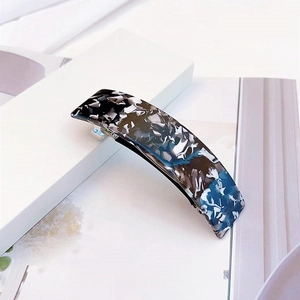Détail de la barrette en acétate avec motifs élégants de marbre noir et bleu ciel