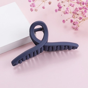 Matte navy blue large crossover hair claw clip on a soft pink minimalist background