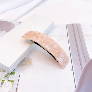 Détail d'une barrette élégante en acétate rose avec mécanisme à ressort en métal