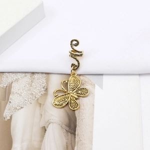 Detail of golden butterfly dreadlock charm with textured wings and spiral hook accessory