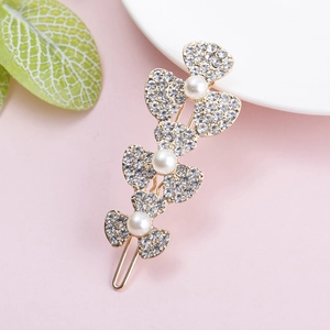 Detailed view of golden butterfly hair clip with white pearls and sparkling rhinestones