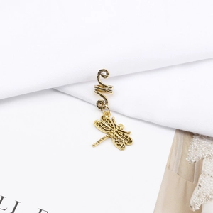 Detailed macro shot of vintage gold dragonfly charm and spiral hair ring for braids