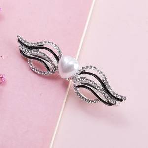 Detail of heart pearl hair clip with rhinestone wings and black enamel finish