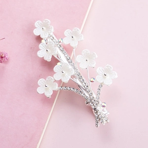 Close-up of a silver floral hair clip with white petals and shimmering rhinestones