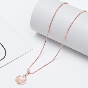 Detail van een roségouden ketting met opaal waterdruppel hanger op een wit plateau