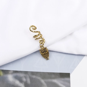 Detailed close-up of a bronze owl pendant on a spiral hair ring for dreadlocks