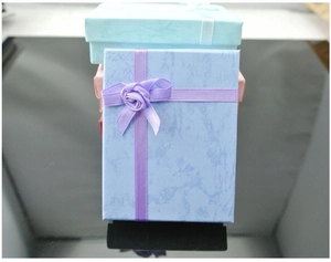 Vertical stack of marble texture jewelry gift boxes with satin ribbon flower knots