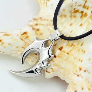 Macro view of silver claw pendant with zircon on white seashell and black cord