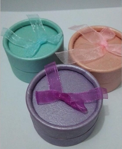 Three small round jewelry gift boxes in pastel colors with matching organza ribbon bows